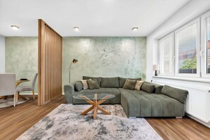 A modern living room with a sectional sofa, a glass coffee table, and a wooden partition.