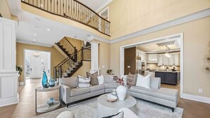 A spacious living room with a large sectional sofa, a round coffee table, and a staircase leading to an upper level.