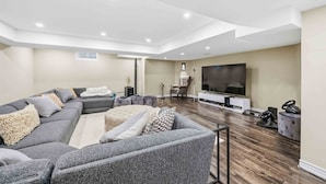 A modern living room with a sectional sofa, a flat-screen TV, and a sound system.