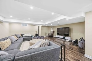A modern living room with a sectional sofa, a flat-screen TV, and a sound system.