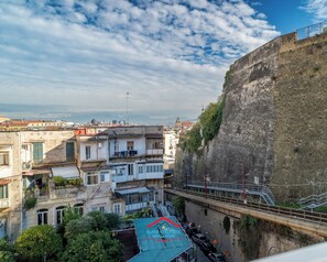 A view of a cityscape with a prominent stone wall on the right, a bridge in the foreground, and buildings with balconies and terraces. - Star-Rated Suite in Naples' Historic Center: Triple Room (Napoli)
