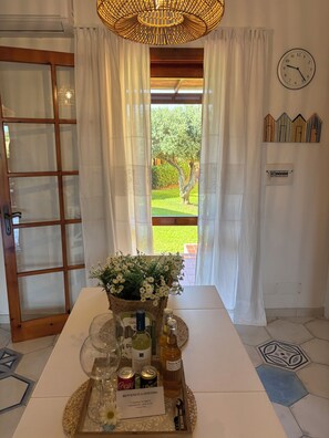 Ein Hotelzimmer mit Blick auf einen Garten, ein Tisch mit einer Ablage für Annehmlichkeiten, eine Wanduhr und eine dekorative Deckenleuchte.
