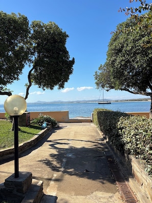 A pathway leading to a body of water with a sailboat visible in the distance.