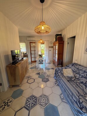 Una habitación con cama, escritorio, televisor y lámpara colgante.