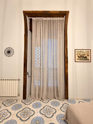Ein Zimmer mit Holztür, Heizkörper, fußbodenhohen Wandfliesen, einem Bett und Wandgestaltungen.