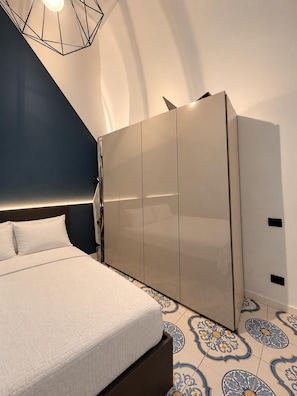 Ein Schlafzimmer mit einem Bett, einem Kleiderschrank und einem geometrischen Lampenschirm.