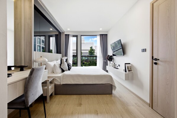 Ein modernes Schlafzimmer mit Bett, Schreibtisch, Stuhl und Fernseher an der Wand.