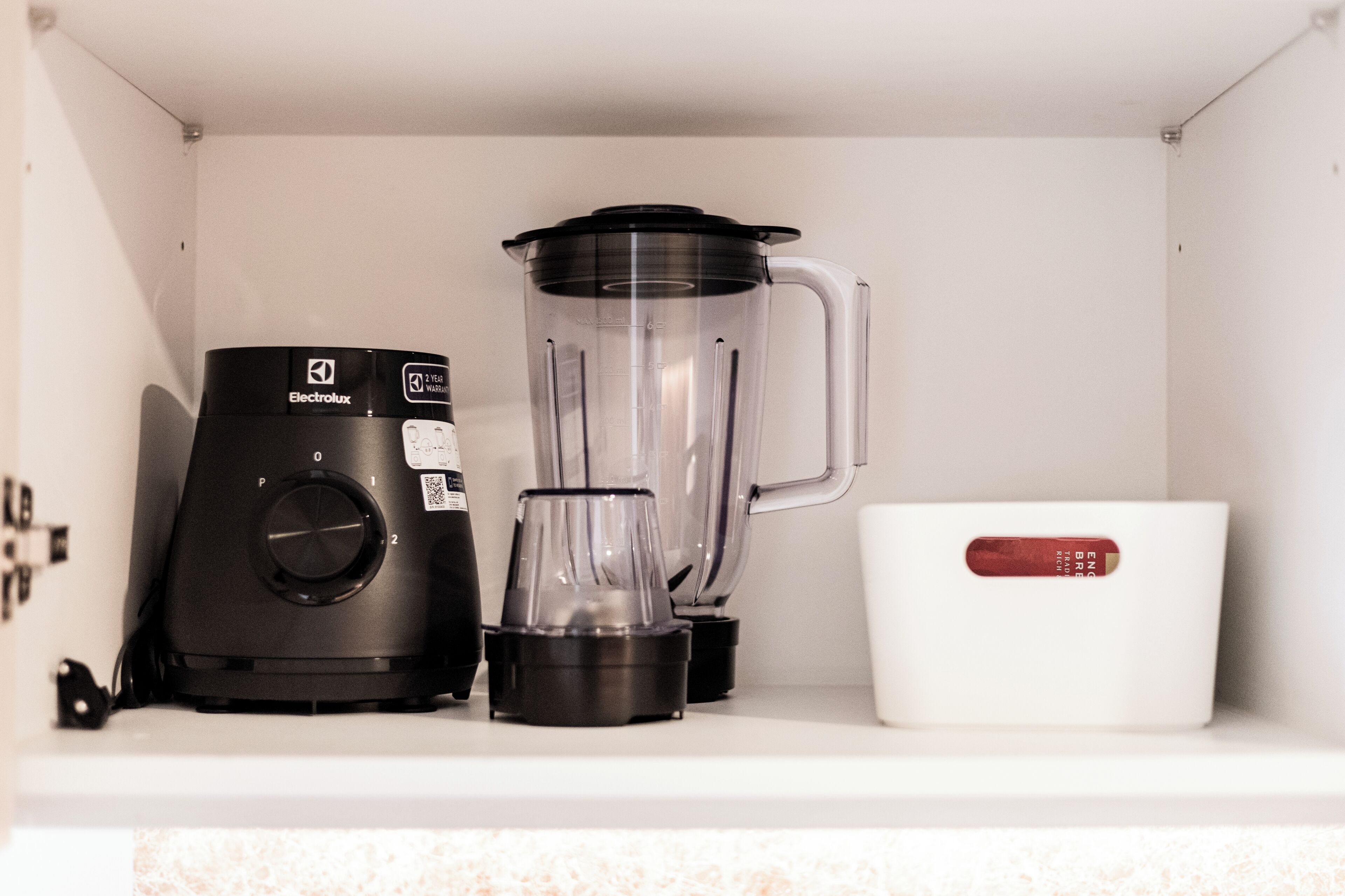 Una cocina con una licuadora Electrolux negra y una cafetera blanca sobre la encimera.