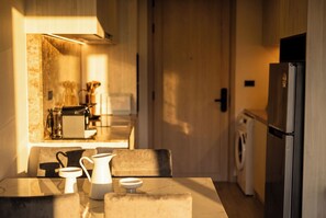Eine Küche mit Esstisch, Stühlen, einer Kaffeemaschine und einem Kühlschrank.