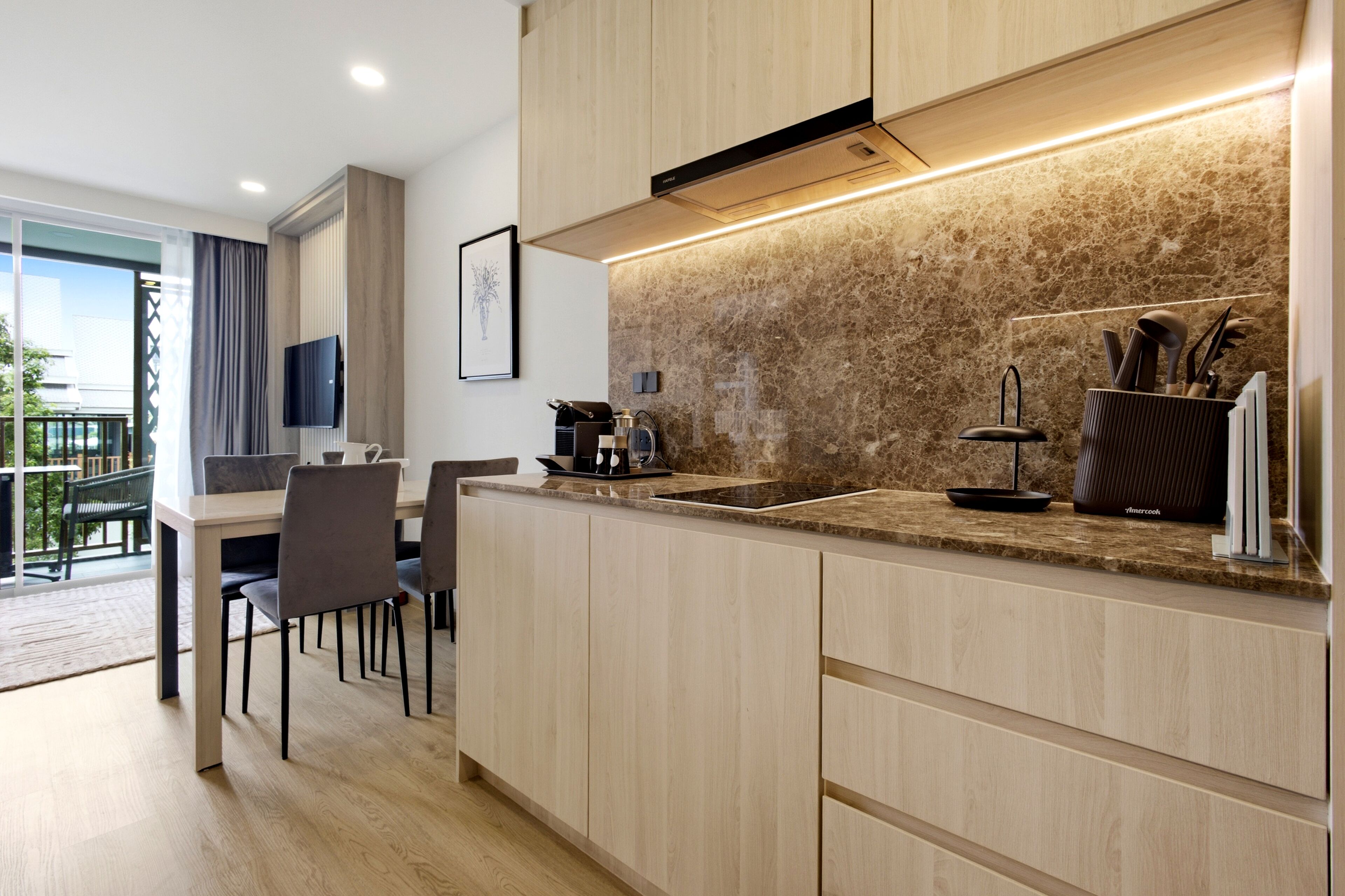A modern kitchen with a marble backsplash, a built-in stove, and a dining area with a table and chairs.