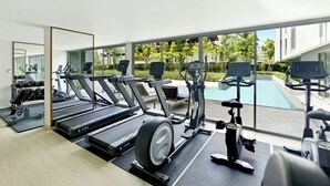 A modern gym with treadmills, elliptical machines, and a pool view. - Bangtao Laguna Apartment 42 sq.m (Thalang District)
