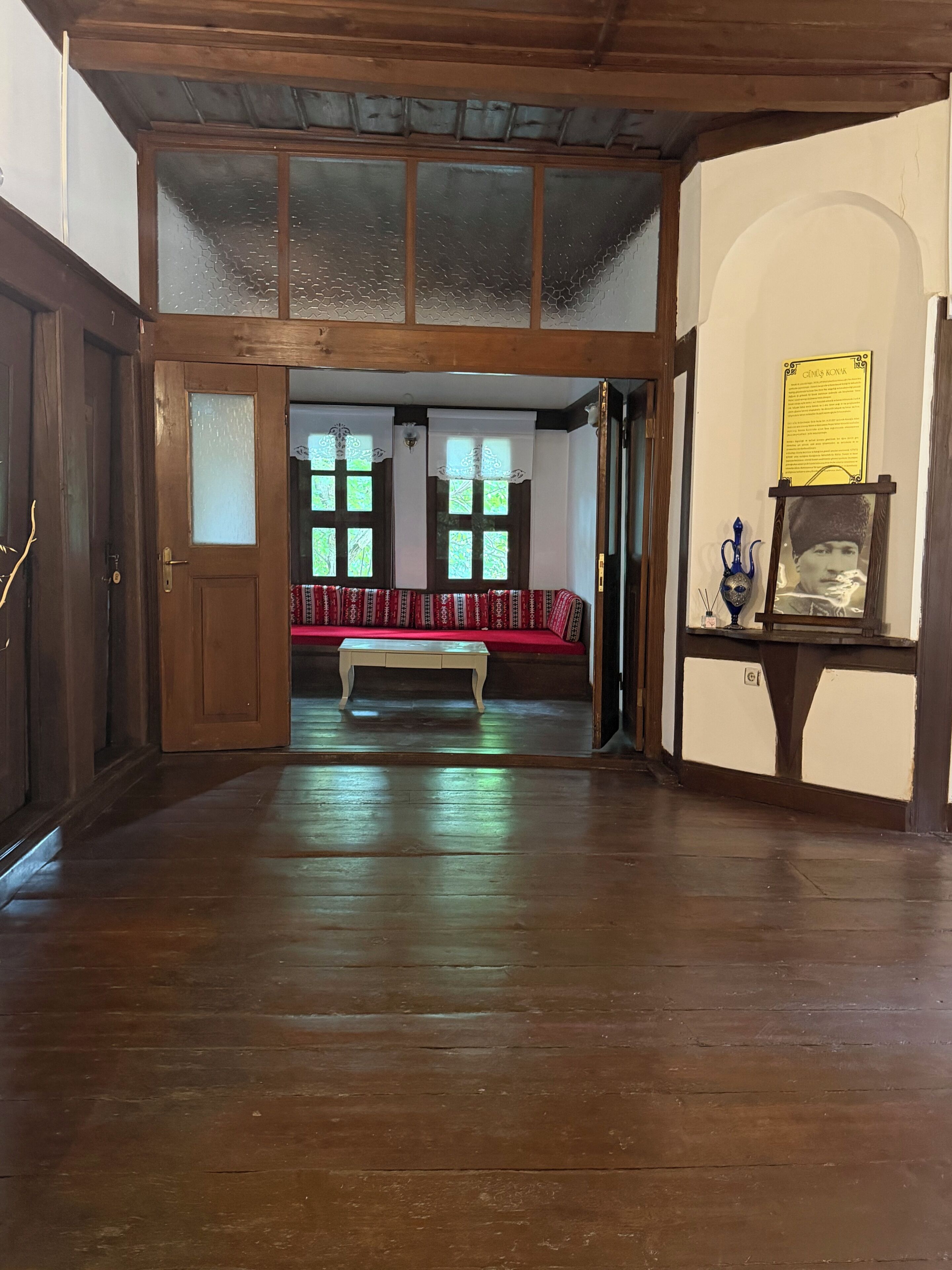 A room with a wooden floor, a bench, and a wall-mounted display case.