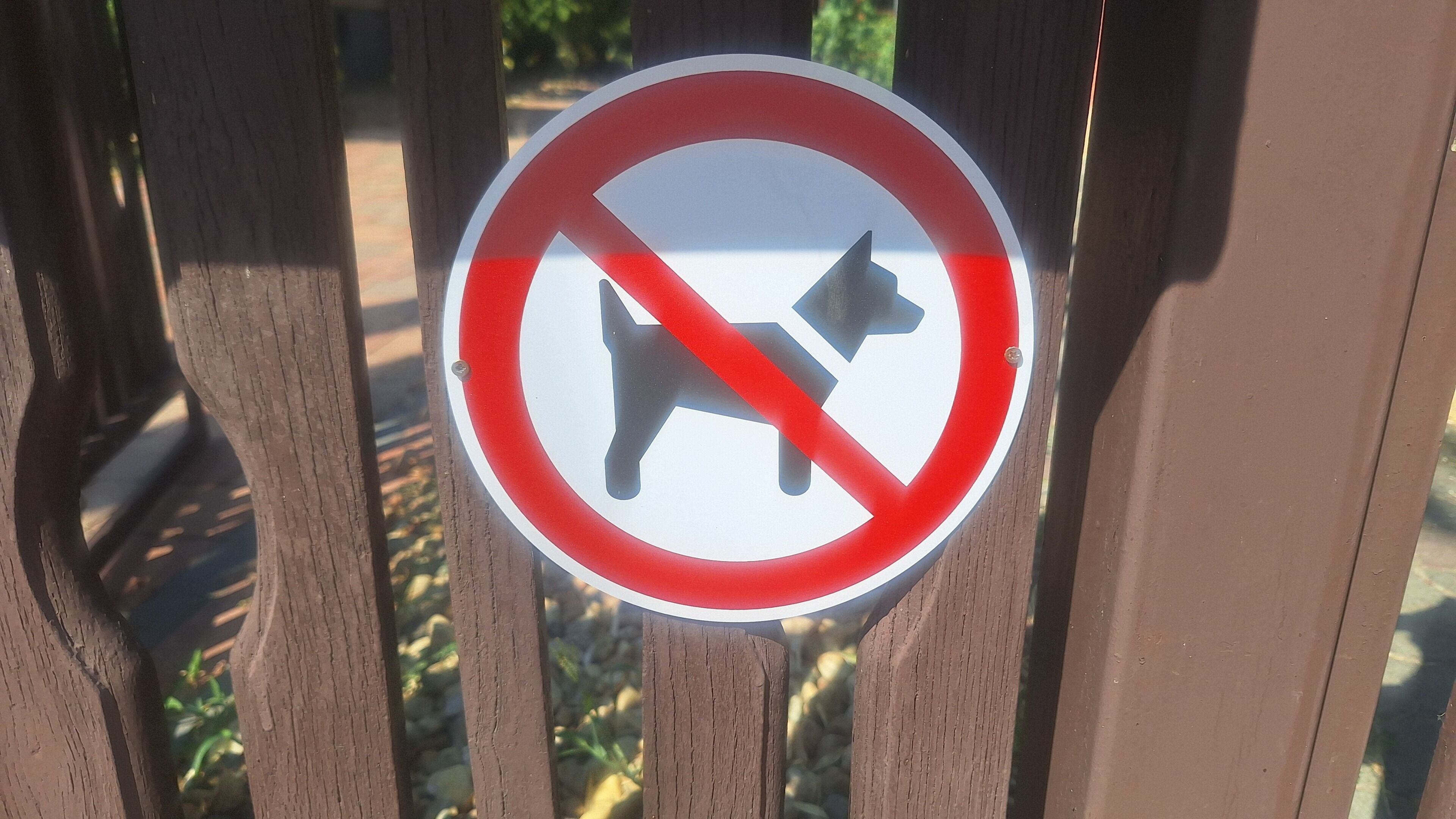 Un panneau indiquant qu’il est interdit d’y entrer avec un chien, fixé à une clôture en bois.