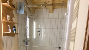 A bathroom with a wooden vanity, a glass shower enclosure, and a white rug on the floor. - Apartment with Balconies (sleeps 6) (Saint-Michel-de-Maurienne)