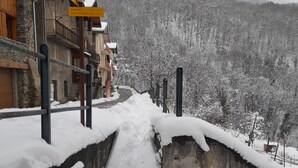 A snow-covered path leading to a building with a stone wall and wooden railings. - Apartment with Balconies (sleeps 6) (Saint-Michel-de-Maurienne)