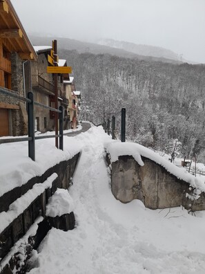 A snow-covered path leading to a building with a stone wall and wooden railings. - Apartment with Balconies (sleeps 6) (Saint-Michel-de-Maurienne)
