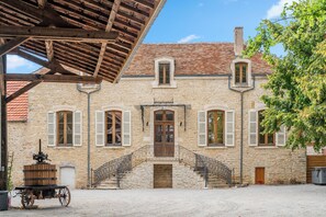 A stone building with a tiled roof, a wooden staircase, and a cart. - A 10-minute drive from Beaune, on a vineyard estate, a charming Burgundian house. (Corcelles-les-Arts)
