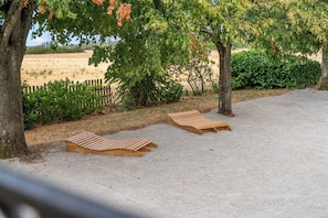 Two wooden lounge chairs on a gravel surface, surrounded by trees and a fence. - A 10-minute drive from Beaune, on a vineyard estate, a charming Burgundian house. (Corcelles-les-Arts)