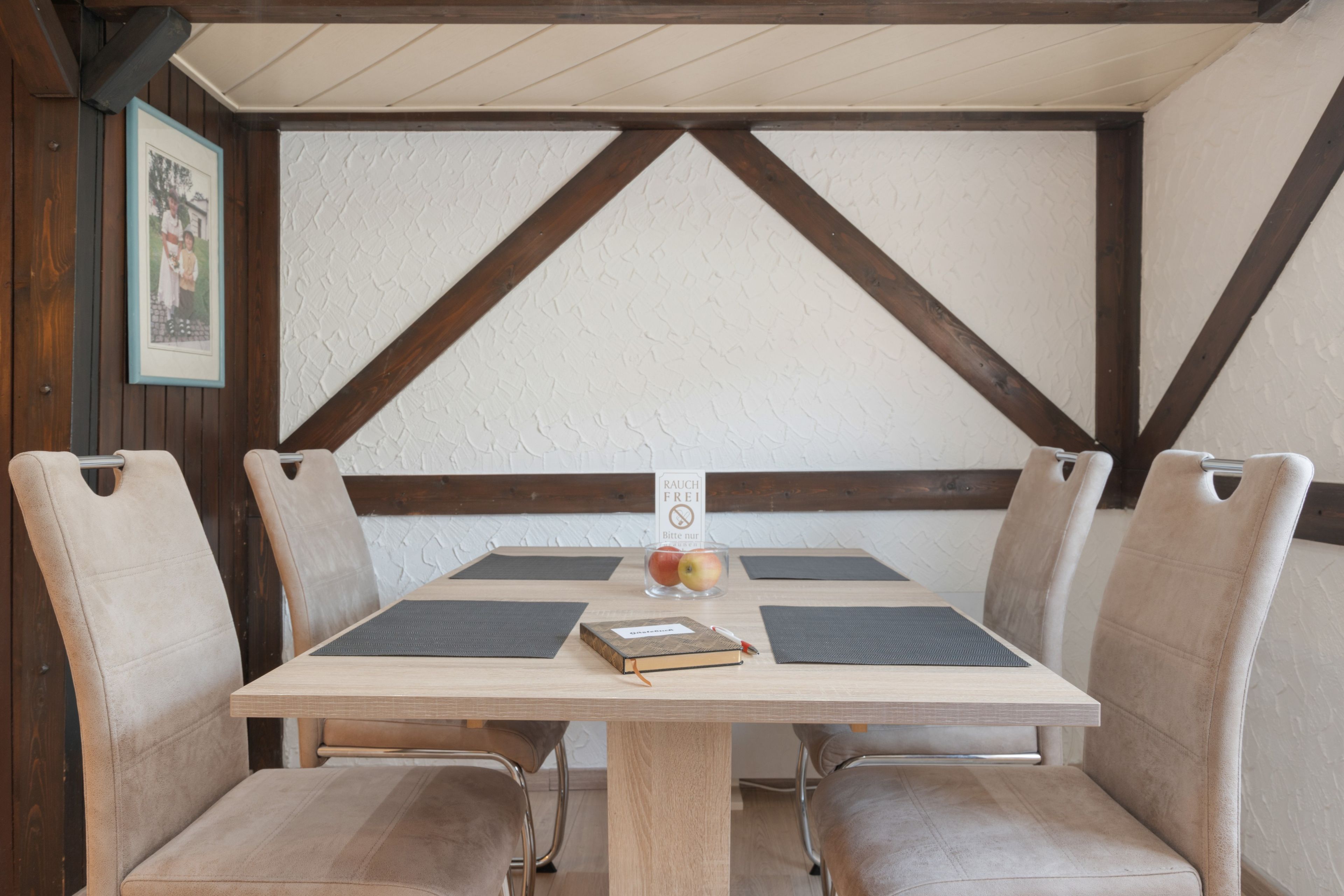 Una mesa de comedor con cuatro sillas, un libro y un vaso de fruta.