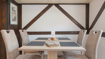 Una mesa de comedor con cuatro sillas, un libro y un vaso de fruta.