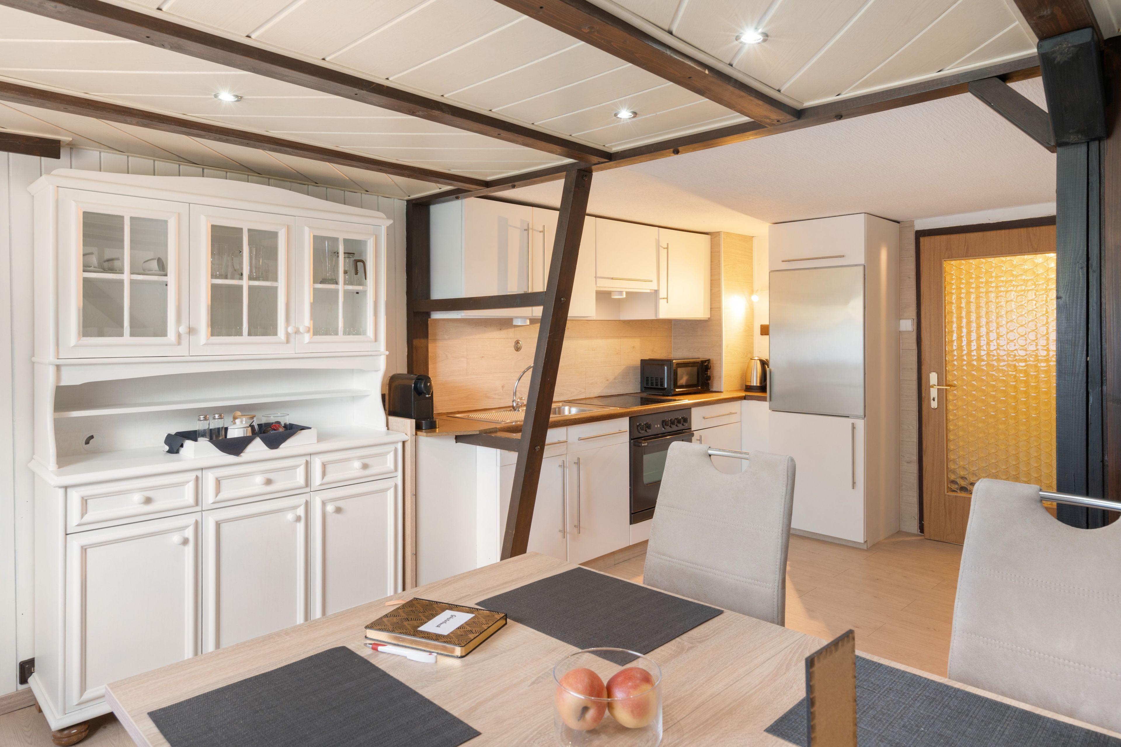 A modern kitchen with white cabinets, a built-in oven, and a refrigerator.