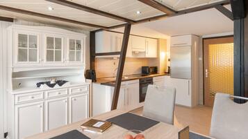 A modern kitchen with white cabinets, a built-in oven, and a refrigerator.