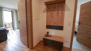 Une pièce dotée d’un plancher en bois, d’un banc intégré avec espace de rangement, d’une étagère fixée au mur et d’une porte.