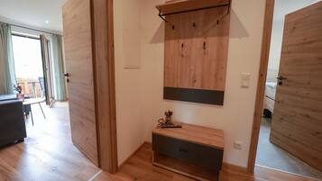 Ein Zimmer mit Holzboden, einer eingebauten Sitzbank mit Stauraum, einem Wandregal und einer Tür.