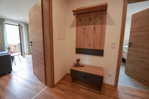 Una habitació amb terres de fusta, una banca integrat amb espai d'emmagatzematge, una prestatgeria penjada a la paret i una porta.