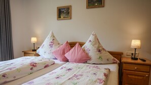 Un lit double avec une literie à motifs floraux, deux tables de chevet avec des lampes et une tête de lit en bois.