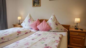 A double bed with floral bedding, two nightstands with lamps, and a wooden headboard.