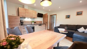 Un espace de vie moderne comprenant une table à manger en bois, un canapé bleu et un coin cuisine avec des meubles en bois et un four encastré.