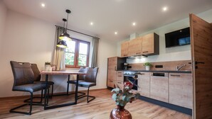 Une cuisine moderne avec des meubles en bois, un four encastré et un téléviseur à écran plat.