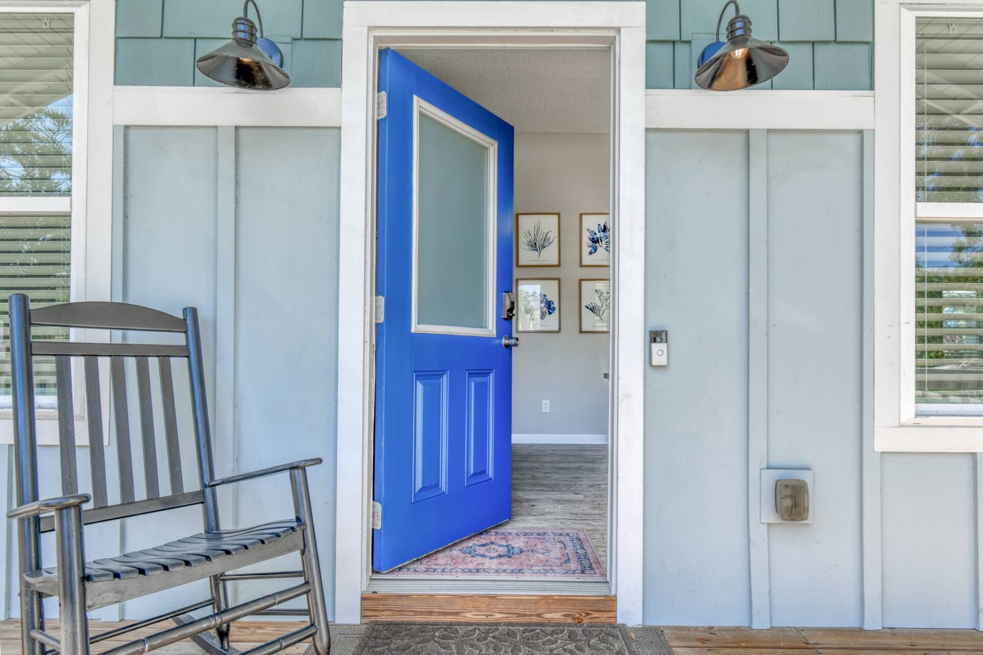 A blue door leading to a room with a wooden bench and a rug.