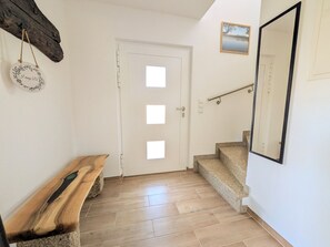 A staircase with a handrail, a bench, and a door with a window. - 2-Bedroom Vacation Rental with a Balcony (Saaldorf-Surheim)