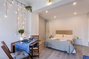 Ein modernes Schlafzimmer mit Bett, Nachttisch und einem Essbereich mit Tisch und Stühlen.