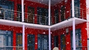Una persona parada en un patio nevado con un edificio que tiene varios balcones y ventanas.