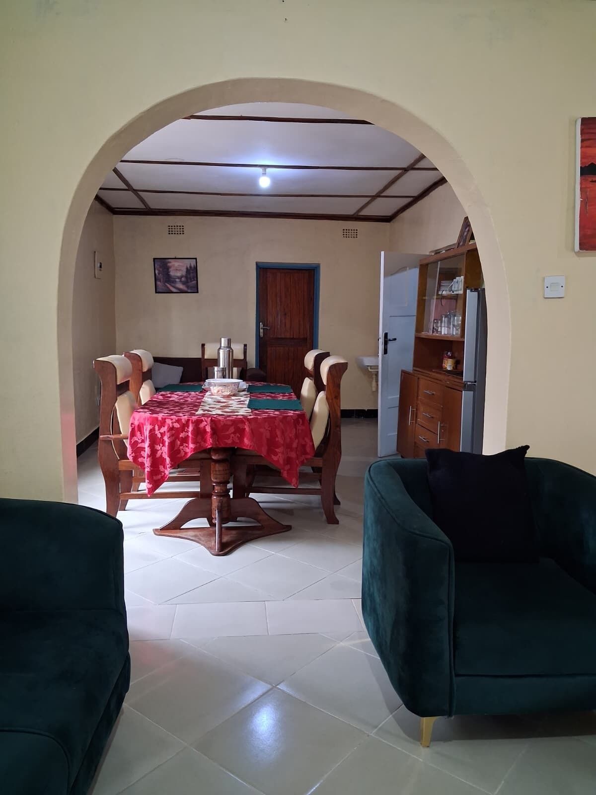 Un comedor con una mesa dispuesta para cuatro, una puerta y un aparador con copas.