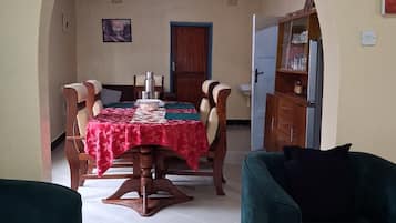 Un comedor con una mesa dispuesta para cuatro, una puerta y un aparador con copas.