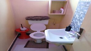 Pieni kylpyhuone, jossa on wc, pesuallas ja pesualtaan yläpuolella oleva hylly.