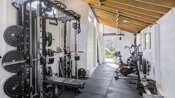 A gym with weightlifting equipment, cardio machines, and a bench.