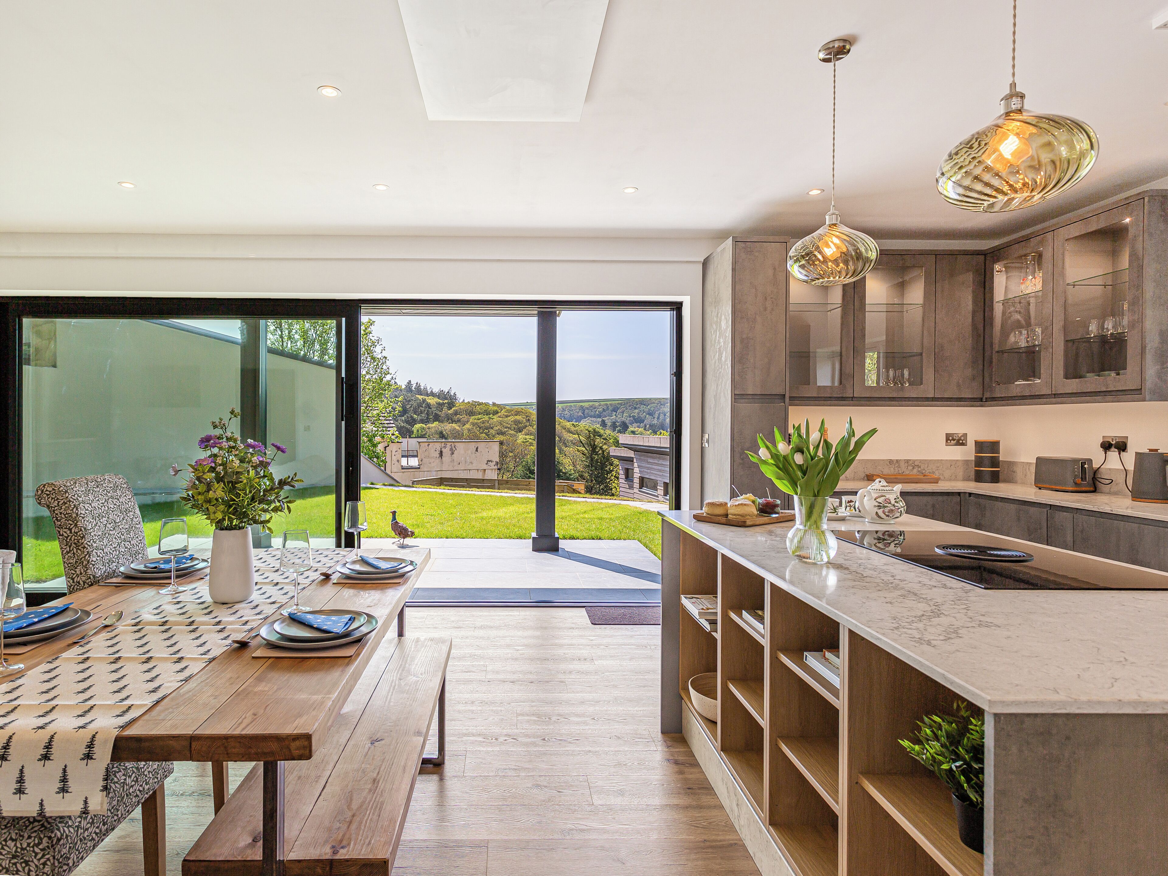 Una cocina moderna con una isla grande, suelo de madera y vistas al exterior.