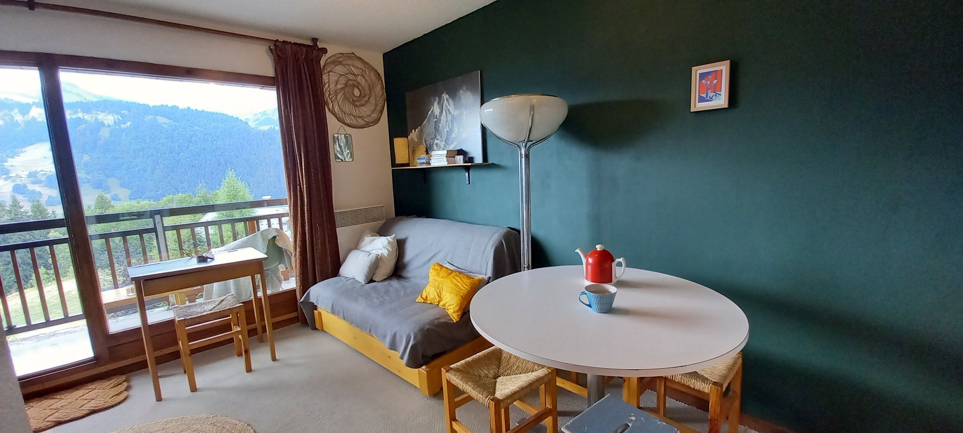 Una habitación con balcón, sofá, mesa y lámpara.