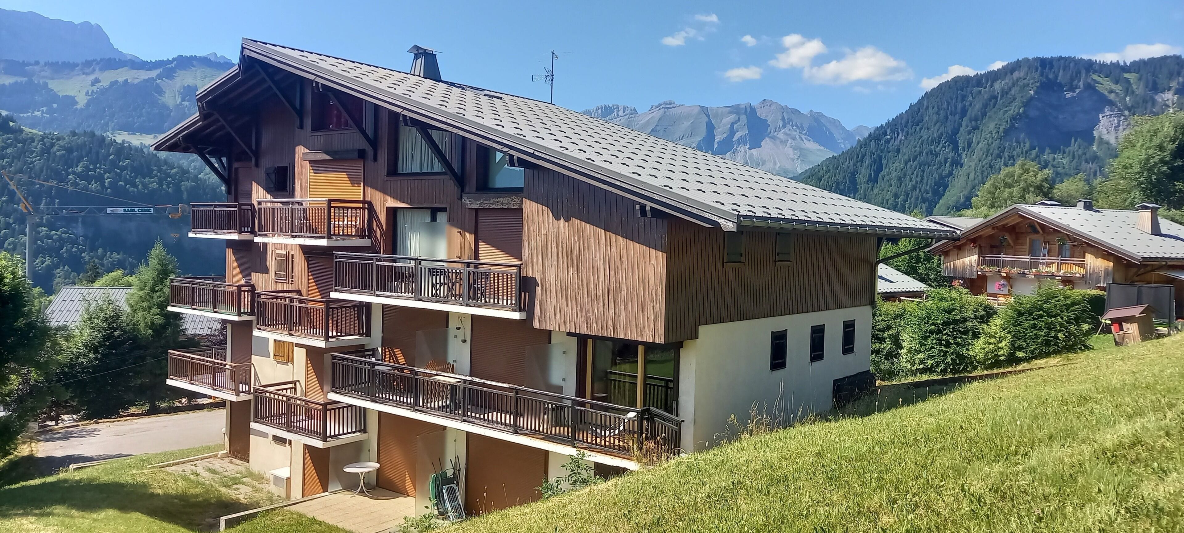 Un chalet à plusieurs étages, doté de balcons, situé dans un cadre montagneux.