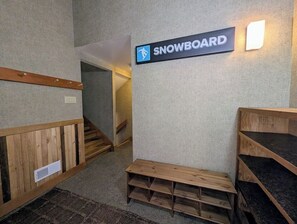 En gang med et skilt der står 'SNOWBOARD' og træbænke.