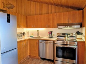 Une cuisine moderne avec des meubles en bois, des appareils électroménagers en acier inoxydable et un lave-vaisselle.