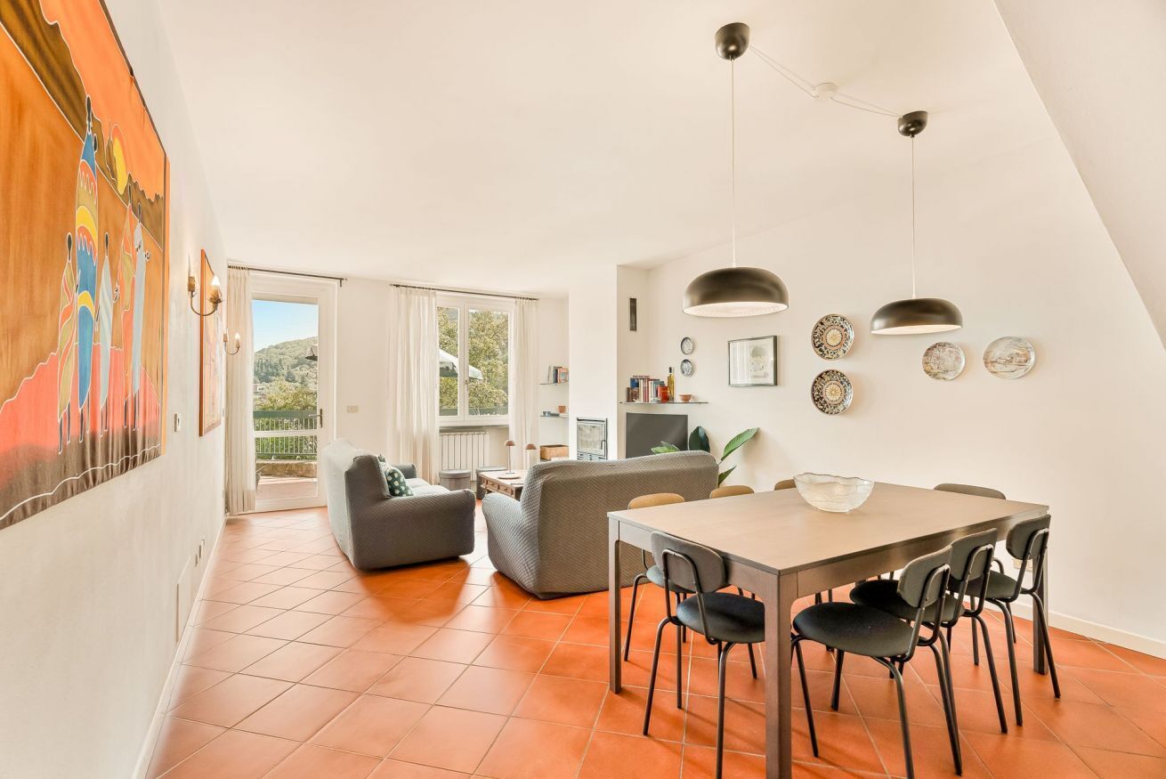 Un vaste espace de vie comprenant une table à manger, des canapés et une vue dégagée sur l’extérieur grâce à une porte vitrée.