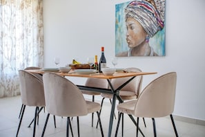 A dining area with a wooden table, four chairs, and a painting on the wall. - Beautiful, fully equipped 3BR in Sliema w/Balcony (Tas-Sliema)