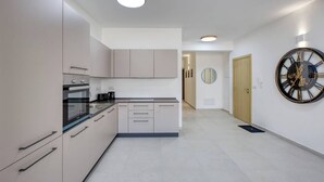 A modern kitchen with a built-in oven, a coffee maker, and a wall-mounted clock. - Beautiful, fully equipped 3BR in Sliema w/Balcony (Tas-Sliema)