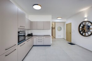 Eine moderne Küche mit Einbauofen, Kaffeemaschine und Wanduhr.